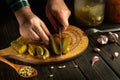 Slicing pickled cucumbers with a knife in the hand of a chef on a cutting board. The concept of preparing a delicious salad of