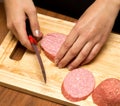 Slicing sausage with a knife on the board