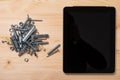 Slide of bolts and nuts and a tablet with an empty screen lie on the table Royalty Free Stock Photo