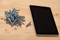 Slide of bolts and nuts and a tablet with an empty screen lie on the table Royalty Free Stock Photo