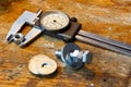 Slide caliper with round scale and bolt with nuts on the workbench in workshop Royalty Free Stock Photo