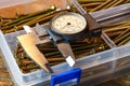 Slide caliper with round scale and screws in storage box on a wooden table Royalty Free Stock Photo