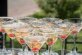 A slide of champagne. Pyramid of champagne glasses with red cherries.