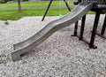 stainless steel slide and swings on the playground in the park in gray pebbles Royalty Free Stock Photo