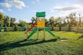 Slide and swings with a wooden house on children playground. Outdoors games for kids. Summer bright day Royalty Free Stock Photo