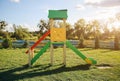 Slide and swings with a wooden house on children playground. Outdoors games for kids. Summer bright day Royalty Free Stock Photo