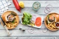 Sliders and fries on wooden plates with a platter of toppings in the middle. Royalty Free Stock Photo