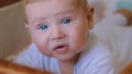 Portrait of cute newborn baby boy lying on tummy in his cradle and smiling