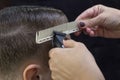 Sliding rear view shot of a barber using a clipper giving a haircut to male client. Royalty Free Stock Photo