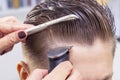 Sliding rear view shot of a barber using a clipper giving a haircut to male client. Royalty Free Stock Photo