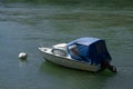 Cabin yacht with blue hood and outboard motor bobbing in a river Royalty Free Stock Photo