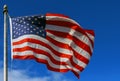 Slight Motion blur American flag against a blue sky with clouds Royalty Free Stock Photo