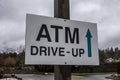 Slightly angled view of a white ATM Drive Up sign with a directional arrow pointing where the drive thru beigns, shot against a Royalty Free Stock Photo