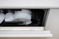 Slightly open dishwasher with utensil and tableware inside Royalty Free Stock Photo