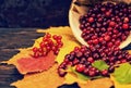 Slightly scattered rowan berries lying on leaves near wooden plate with berries on wooden desk