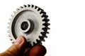 Slightly used alluminium alloy cog wheel from spur gear held in left hand on white background