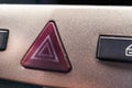 Slightly worn red hazard warning button on the car panel as an important safety element when driving a car