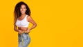 Slim african american woman measuring waist with tape, yellow backdrop Royalty Free Stock Photo