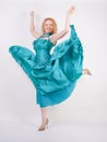 Slim airy girl in flying blue evening dress on white background in Studio