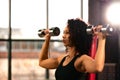 Slim athletic African American woman in sportswear doing exercises with dumbbells on a bench press in the gym, copyspace Royalty Free Stock Photo