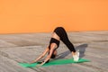 Slim athletic woman in tight sportswear, black pants and top, practicing yoga, standing downward facing dog pose