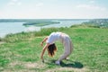 slim beautiful woman doing yoga and stretching outdoors. young woman exercising alone on a river bank. person enjoying Royalty Free Stock Photo