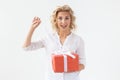 Slim beautiful young blonde girl holding a red gift box in her hands while standing against a white background. Concept