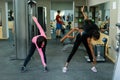 Slim black african-american fitness instructor shows to asian lovely woman how to do exercises. Gym background Royalty Free Stock Photo