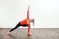 Slim blond woman in tight sportswear practicing yoga, standing in trikonasana triangle pose, training muscles Royalty Free Stock Photo