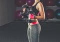 Slim, bodybuilder girl, lifts heavy dumbbell standing in front of the mirror while training in the gym. Royalty Free Stock Photo