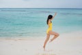 Slim brunette girl in yellow swimsuit jumping on the beach. Royalty Free Stock Photo