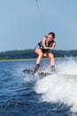 Slim brunette woman riding wakeboard on motorboat wave in lake Royalty Free Stock Photo