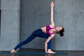 Slim Caucasian girl standing in side angle pose, parsvakonasana, during her yoga routine in gym