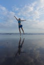 Slim Caucasian woman jumping on the beach. Active lifestyle. Fit and healthy. Happiness and freedom. Young female wearing blue Royalty Free Stock Photo