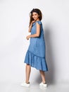 Slim curly model in denim blue dress looking at the camera in full growth. Cute girl in romantic clothes is going on a date