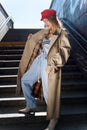 Slim dark-haired model wearing baggy jeans and beige trench coat