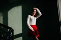 Slim european girl playing with her hair while posing near stairs. Indoor photo of romantic woman in white sweater