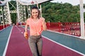 Slim european woman running at stadium with happy face expression. Blithesome girl in gray pants ho