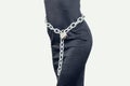 Slim figure girl in black dress. Metal chains on the lock around the waist. Slavery, exploitation of people, lack of freedom, Royalty Free Stock Photo