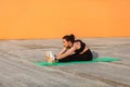 Slim fit attractive girl in tight sportswear, black pants and top, doing stretching exercise touching toes Royalty Free Stock Photo