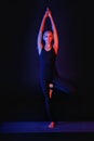 A slim, fit girl is doing stretching sports on a black background in the neon light. Work on yourself exercise fitness exercises Royalty Free Stock Photo