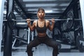 Slim fit woman in sportswear is doing a squat exercise with a barbell on the shoulders of the gym. Healthy lifestyle Royalty Free Stock Photo