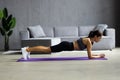 Slim fitnes young woman with ponytail doing planking exercise indoors at home gymnastics