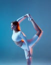 Slim flexible young girl gymnast stretching her leg up, bending lower back. Yoga, pilates workout. Long exposure Royalty Free Stock Photo