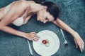 Slim Girl with Anorexia Lying on Sofa with Plate. Royalty Free Stock Photo