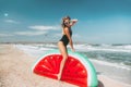 Slim girl playing with inflatable watermelon at sand beach