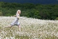 Slim girl in light dress jumping in chamomile field Royalty Free Stock Photo