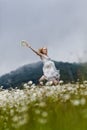 Slim girl in light dress jumping in chamomile field Royalty Free Stock Photo