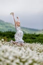 Slim girl in light dress jumping in chamomile field Royalty Free Stock Photo