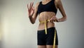 Slim girl measuring waist with tape-line, showing ok, anorexia as mental illness